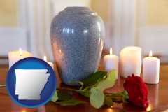 arkansas map icon and cremation urn with red rose and burning candles