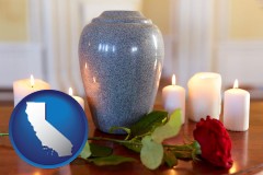 california map icon and cremation urn with red rose and burning candles