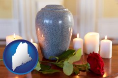 maine map icon and cremation urn with red rose and burning candles