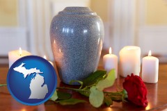 michigan map icon and cremation urn with red rose and burning candles