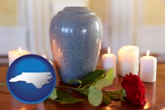 north-carolina map icon and cremation urn with red rose and burning candles