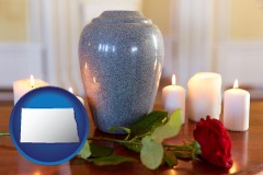 north-dakota map icon and cremation urn with red rose and burning candles