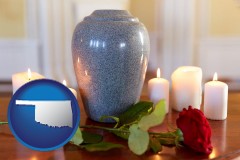 oklahoma map icon and cremation urn with red rose and burning candles