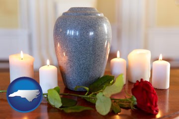 cremation urn with red rose and burning candles - with North Carolina icon
